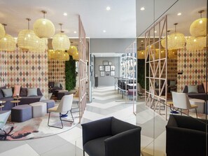 A modern interior with a reception area, seating, and a staircase leading to another level. - ibis Styles Klagenfurt am Woerthersee (Klagenfurt am Woerthersee)