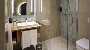 Un baño moderno con ducha de vidrio, lavamanos y retrete.