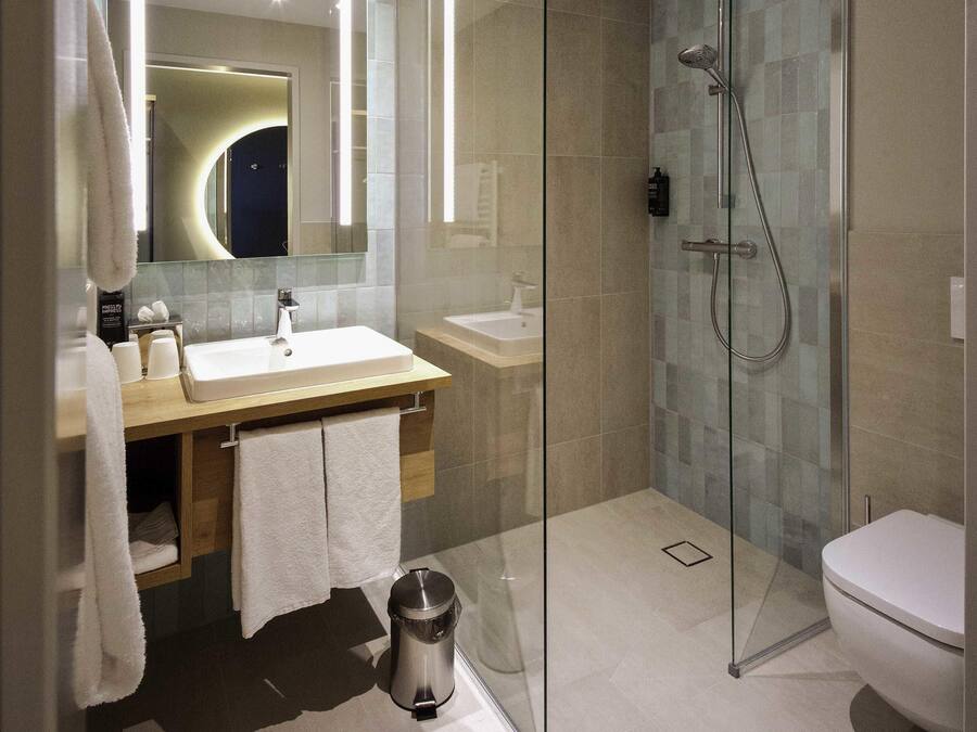 Een moderne badkamer met een douchecabine, een wastafel en een toilet.