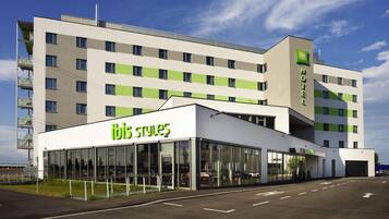 Un hôtel moderne, reconnaissable à son enseigne « ibis Styles » bien visible, à ses grandes fenêtres et à son toit plat.