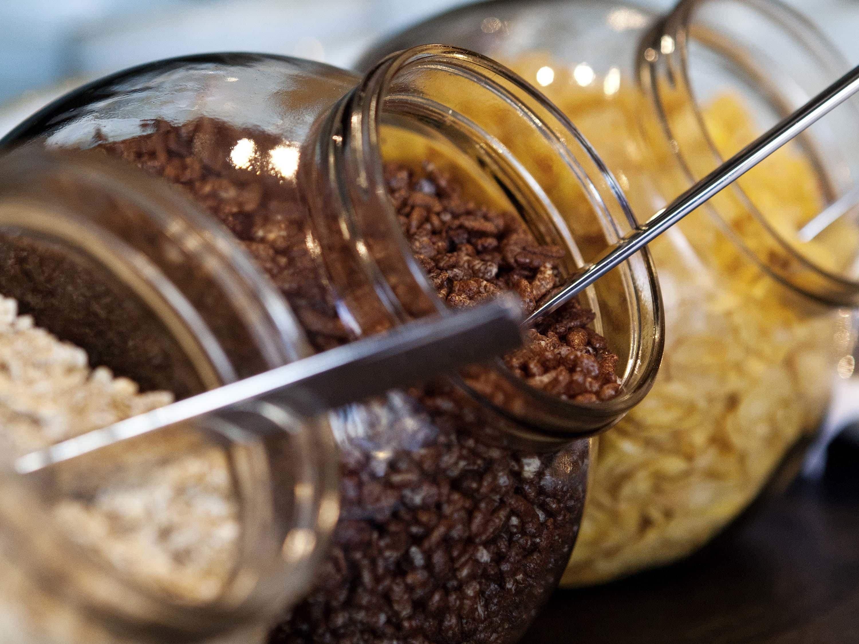 Primer plano de tres frascos de vidrio con cucharones metálicos, que contienen distintos tipos de granos de café.