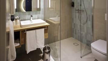 A modern bathroom with a glass-enclosed shower, a sink, and a toilet.