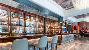 Un espace bar doté d’un comptoir en marbre, de nombreuses bouteilles d’alcool et de tabourets de bar.