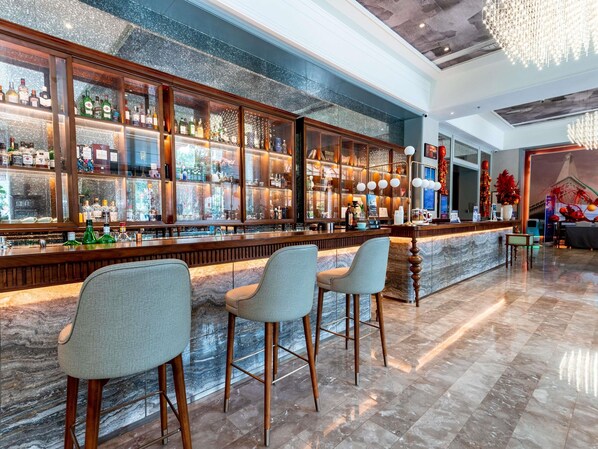 A bar area with a marble countertop, multiple liquor bottles, and bar stools. - Mercure Guangzhou Nansha (Guangzhou)