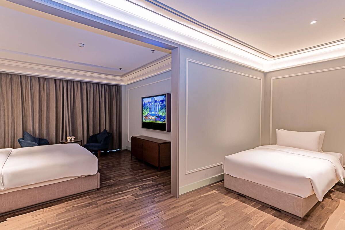 Quarto de hotel com duas camas, televisão, secretária e uma cadeira.