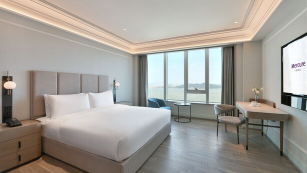 Une chambre d’hôtel moderne avec un grand lit, un bureau et une vue sur la ville.