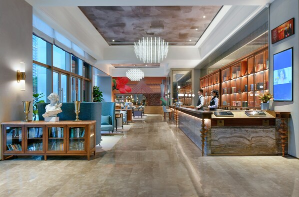 A spacious lobby with a reception desk, seating area, and a large bookshelf. - Mercure Guangzhou Nansha (Guangzhou)