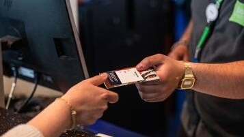 Una persona sostiene una tarjeta en un mostrador, con un monitor de computadora al fondo.