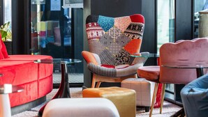 A modern interior with a patterned armchair, a red sofa, and a glass coffee table. - ibis Styles Liege Guillemins (Liege)