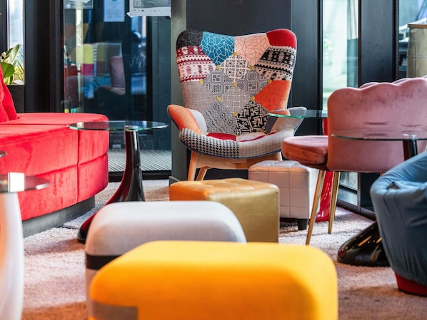 Un interior moderno con un sillón estampado, un sofá rojo y una mesa de centro de vidrio.
