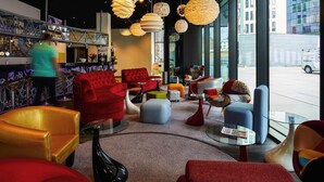 A modern interior with seating, a bar area, and large windows offering a view of the street. - ibis Styles Liege Guillemins (Liege)