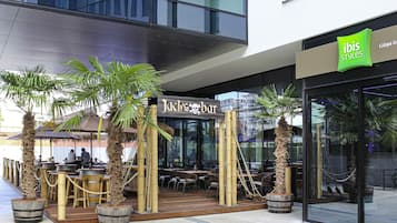 Restaurant amb decoració tropical, palmeres i mobiliari de bambú.