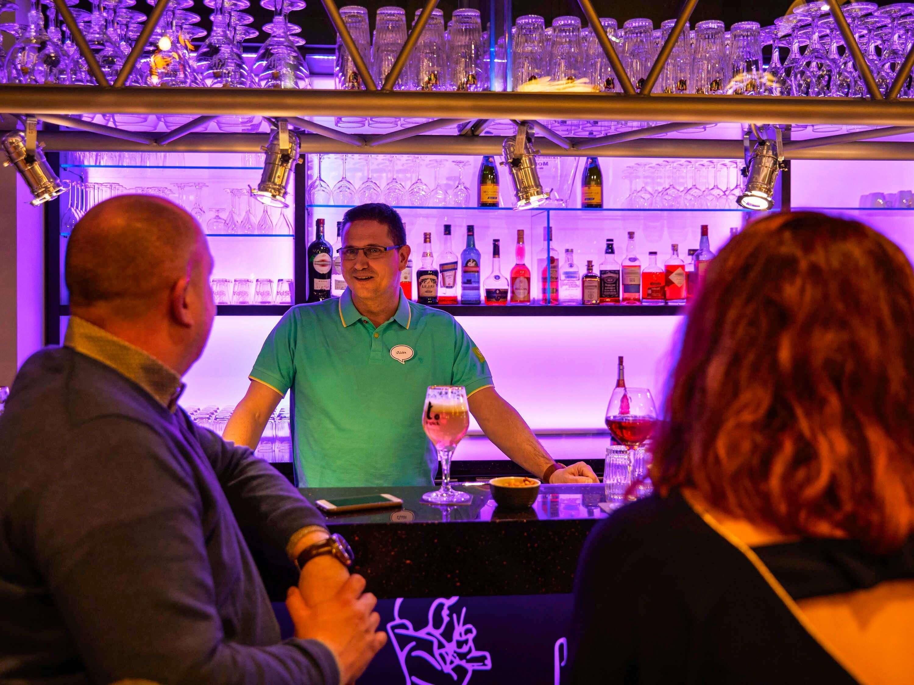 Eine Bar mit einem Barkeeper, Flaschenregalen und Gläsern.