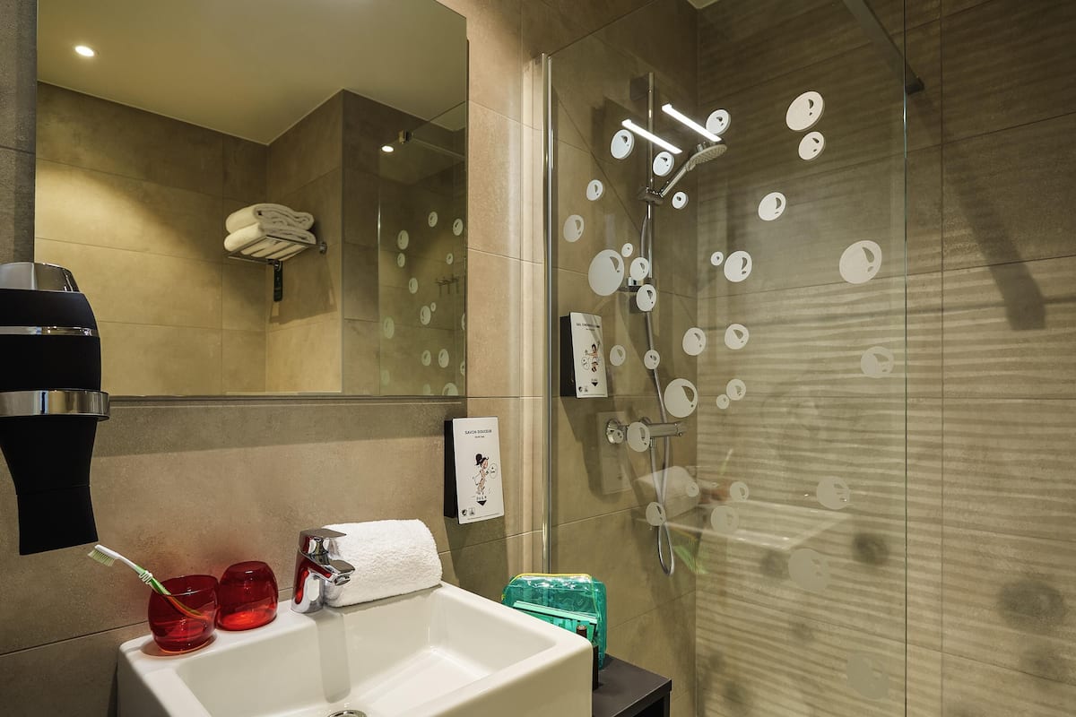 Un baño moderno con ducha de vidrio, un lavamanos con una toalla y un secador de pelo.