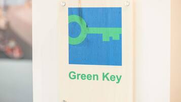 Une enseigne avec un symbole de clé verte et le texte « Green Key » sur un panneau en bois.