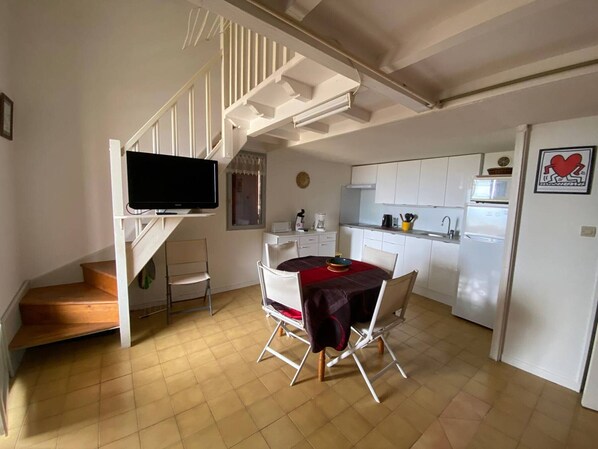 A compact kitchen with white cabinets, a built-in microwave, and a refrigerator.