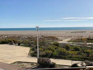 A beach view with a pathway leading to a wooden fence and a lamp post.