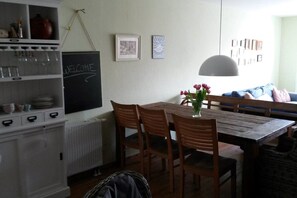 A dining area with a wooden table, chairs, a vase with flowers, a blackboard with 'WELCOME' written on it, and a radiator. - Dream house in Heidelberg city center (Heidelberg)