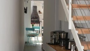 A narrow hallway with a wooden floor leading to a kitchen area with white cabinets and a wooden countertop. - iFicu (Catania)