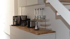 A kitchen counter with a coffee maker, toaster, and glass containers. - iFicu (Catania)