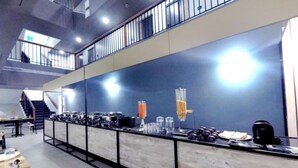 A modern kitchen area with a long counter, various appliances, and a staircase in the background. - VITS Select Kudro Destinn (Mangaluru)