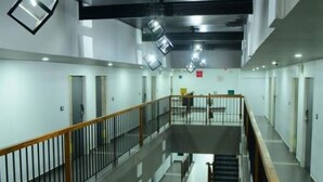 A multi-level interior with a central staircase, metal railings, and a mezzanine with tables and chairs. - VITS Select Kudro Destinn (Mangaluru)