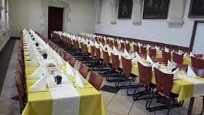 A long dining hall with rows of tables set for a meal, each with a yellow tablecloth and white napkins. - Hostellerie Charles de Foucauld (Viviers)