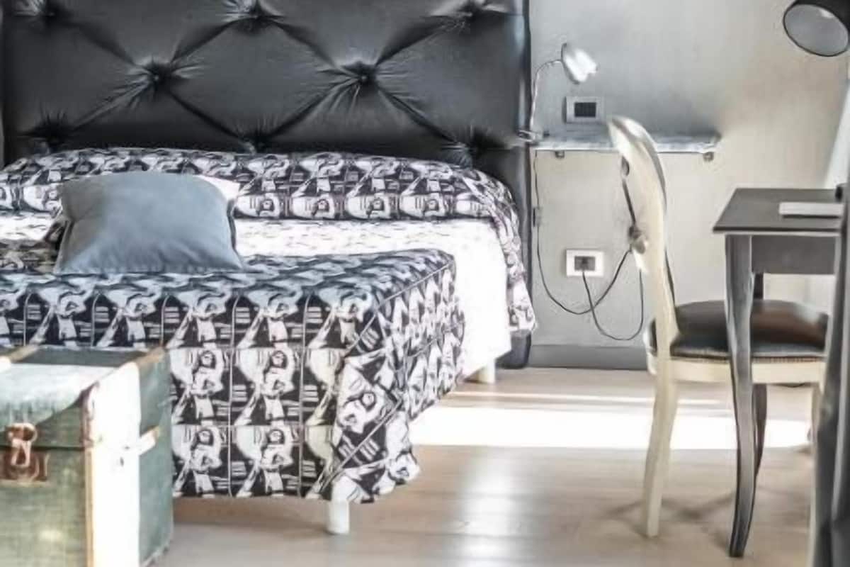 Une chambre à coucher avec un lit, une table de chevet, une chaise et une valise.