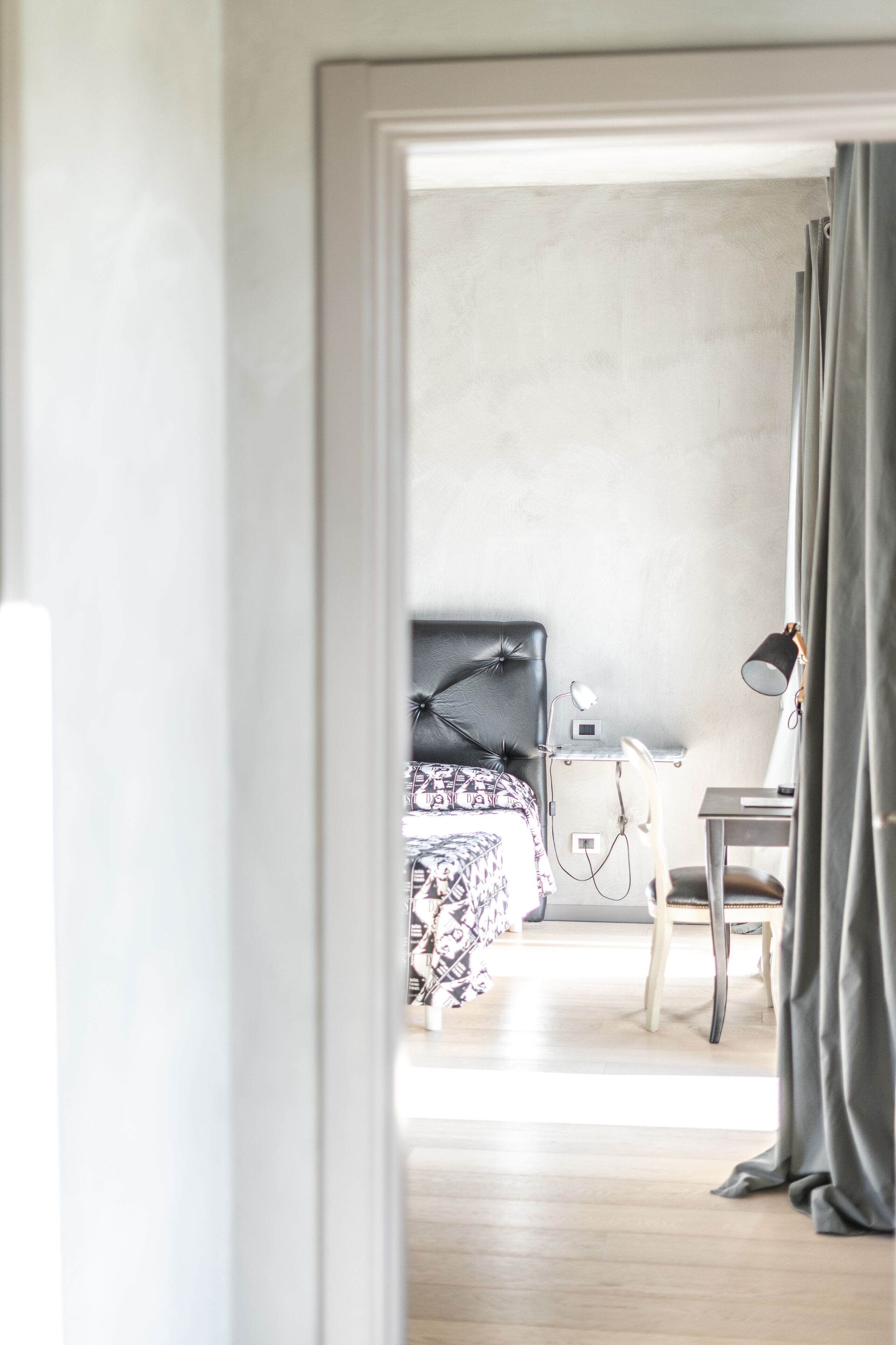 A hotel room with a bed, a desk, a chair, and a lamp.