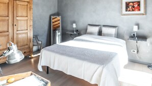 A bedroom with a wooden ceiling, a bed with white linens, a bedside table with a lamp, a wardrobe, and a framed picture on the wall. - Agriturismo Villa Gelso (Vesime)