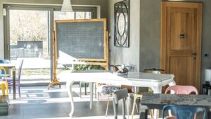 A room with a large window, a wooden door, and a table with chairs. - Agriturismo Villa Gelso (Vesime)