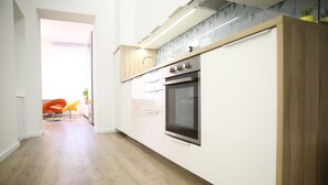 A modern kitchen with white cabinets, a stainless steel oven, and a wooden countertop. - Paulay Central Top Studio (Budapest)
