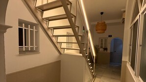 A staircase with a metal railing, a hanging light fixture, and a tiled floor. - Bohemia Sanlucar (Sanlucar de Barrameda)