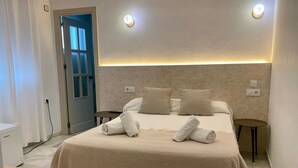 A hotel room with a bed, bedside tables, a small table, and a door. - Bohemia Sanlucar (Sanlucar de Barrameda)