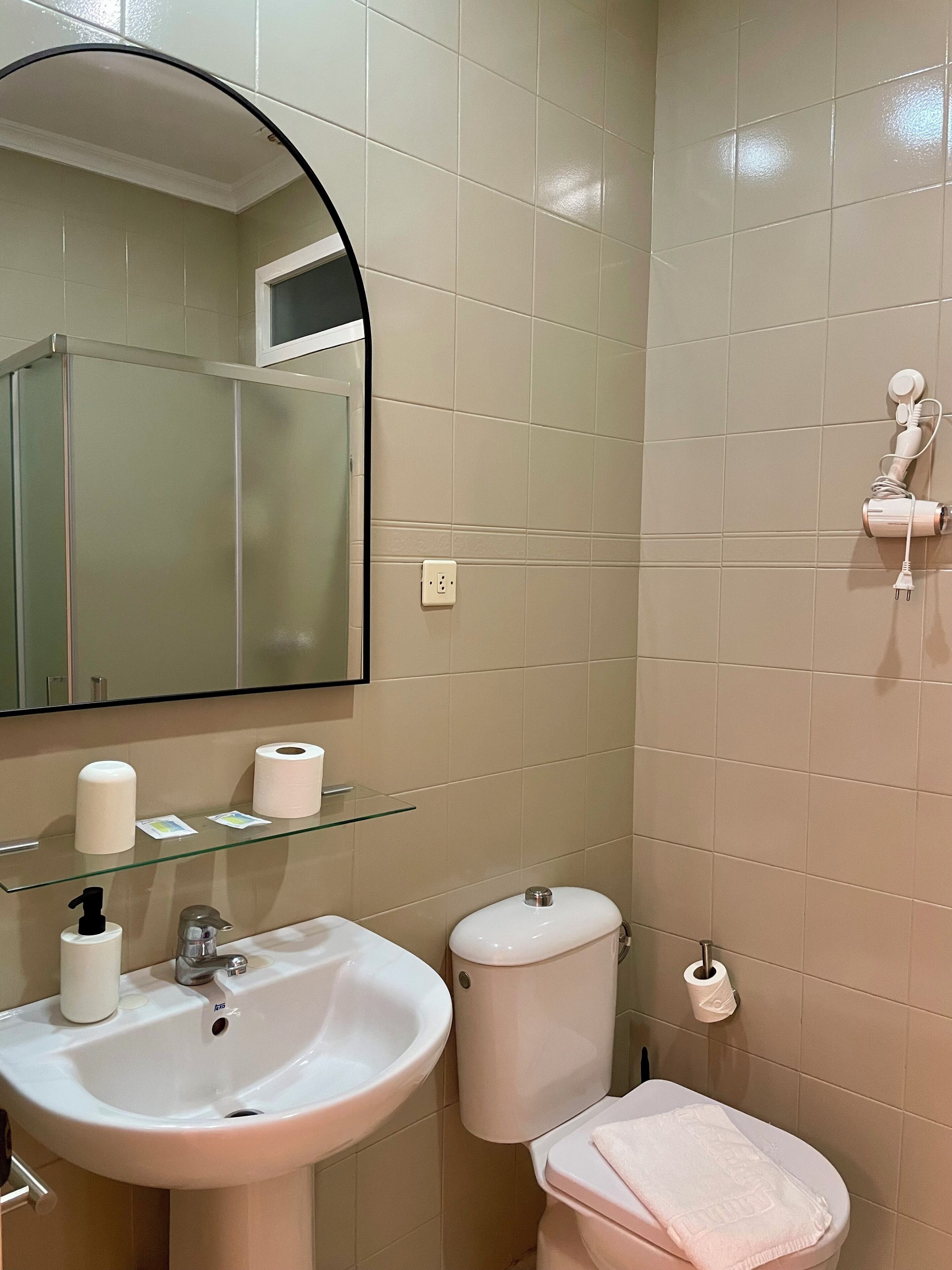 Een badkamer met een wastafel, toilet en spiegel.