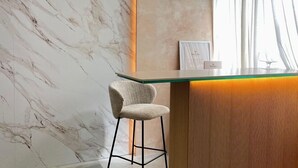 A marble wall, a bar area with a stool, and a framed certificate on the wall. - Bohemia Sanlucar (Sanlucar de Barrameda)