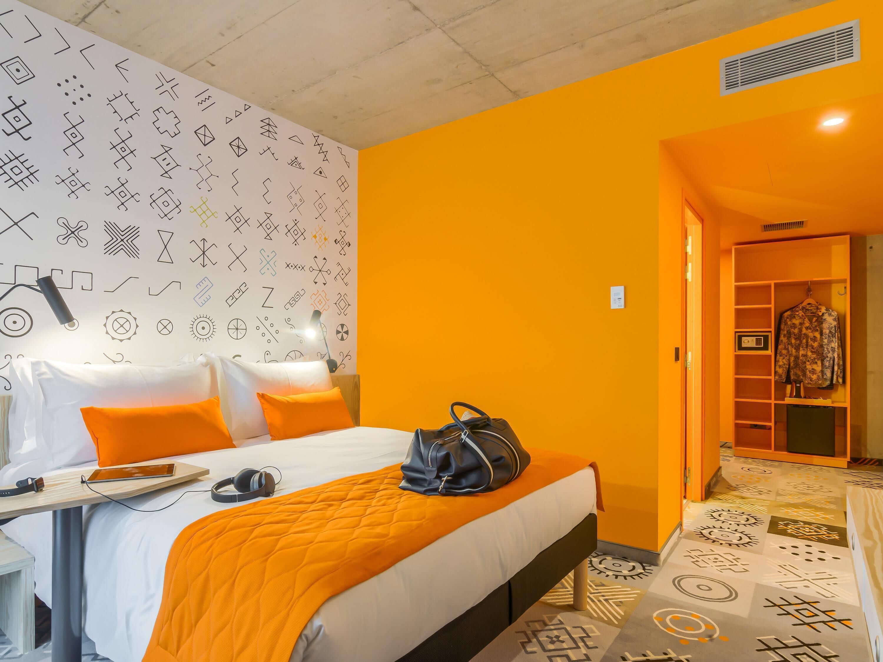Une chambre d’hôtel comprenant un lit, une table de chevet, une lampe et une armoire.