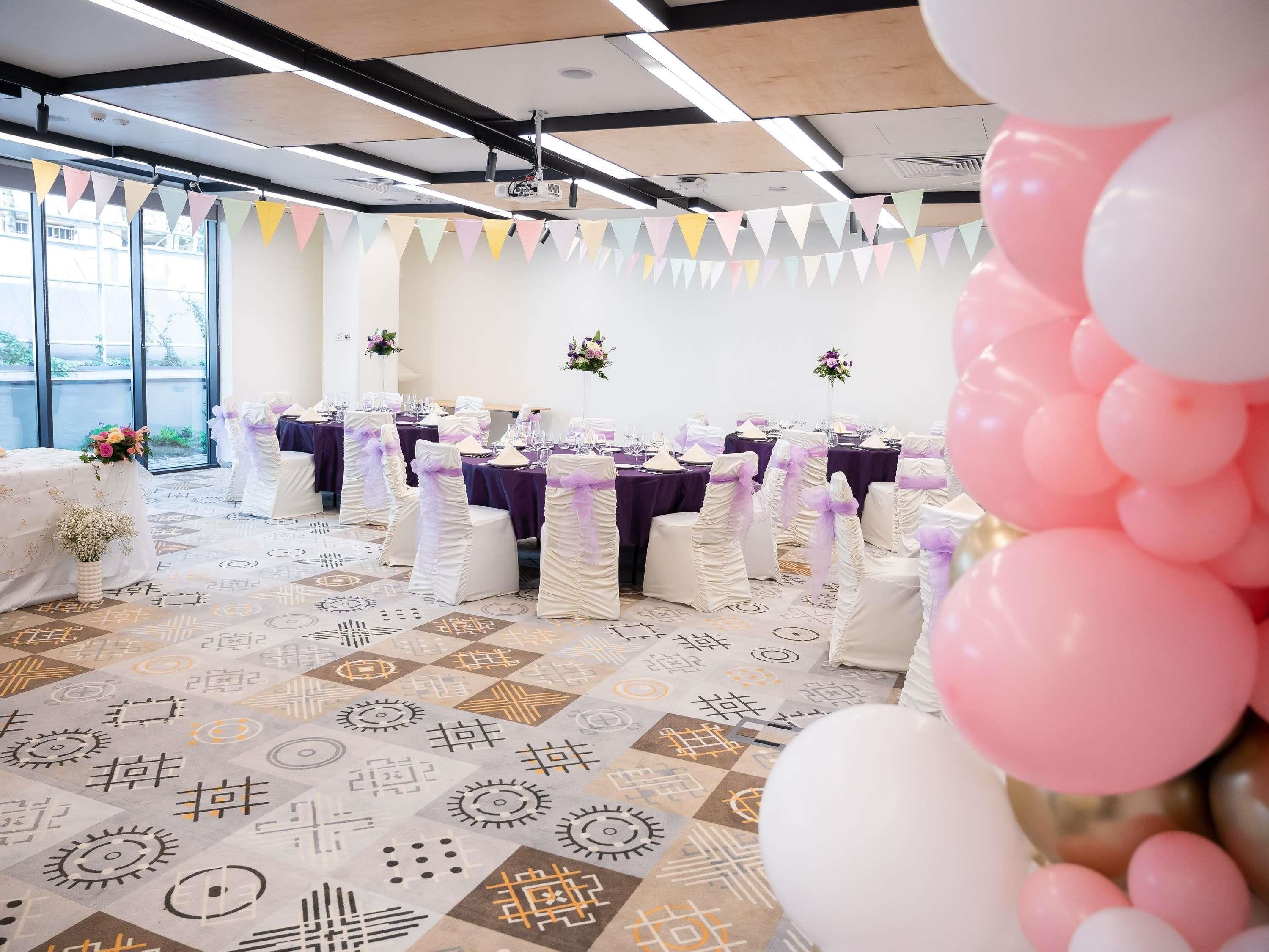 A banquet hall with tables set for an event, featuring a patterned floor and ceiling with exposed beams.