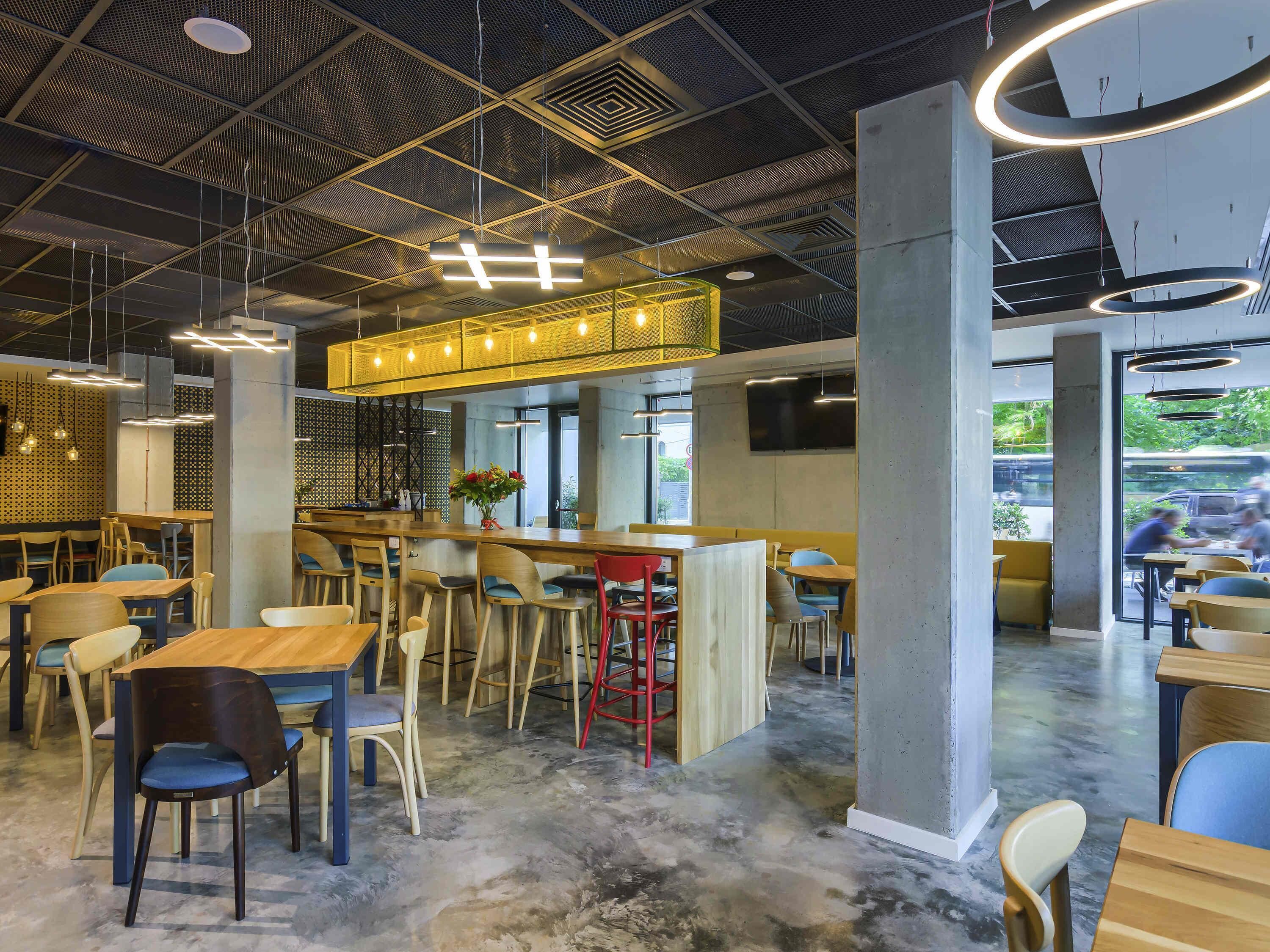 A modern cafe interior with a bar area, wooden tables, and chairs.