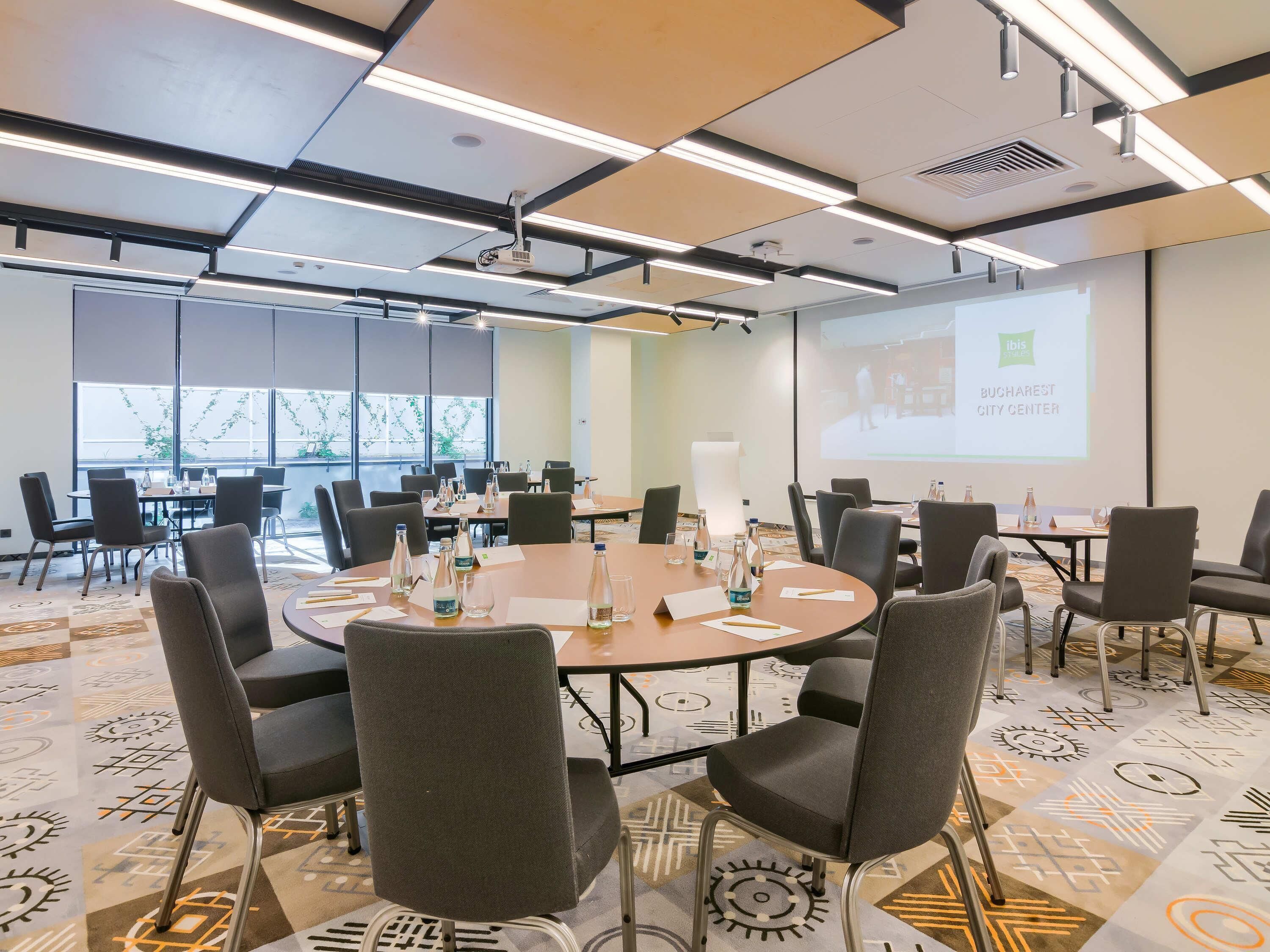 A conference room with a large table, chairs, and a projector screen displaying a presentation.