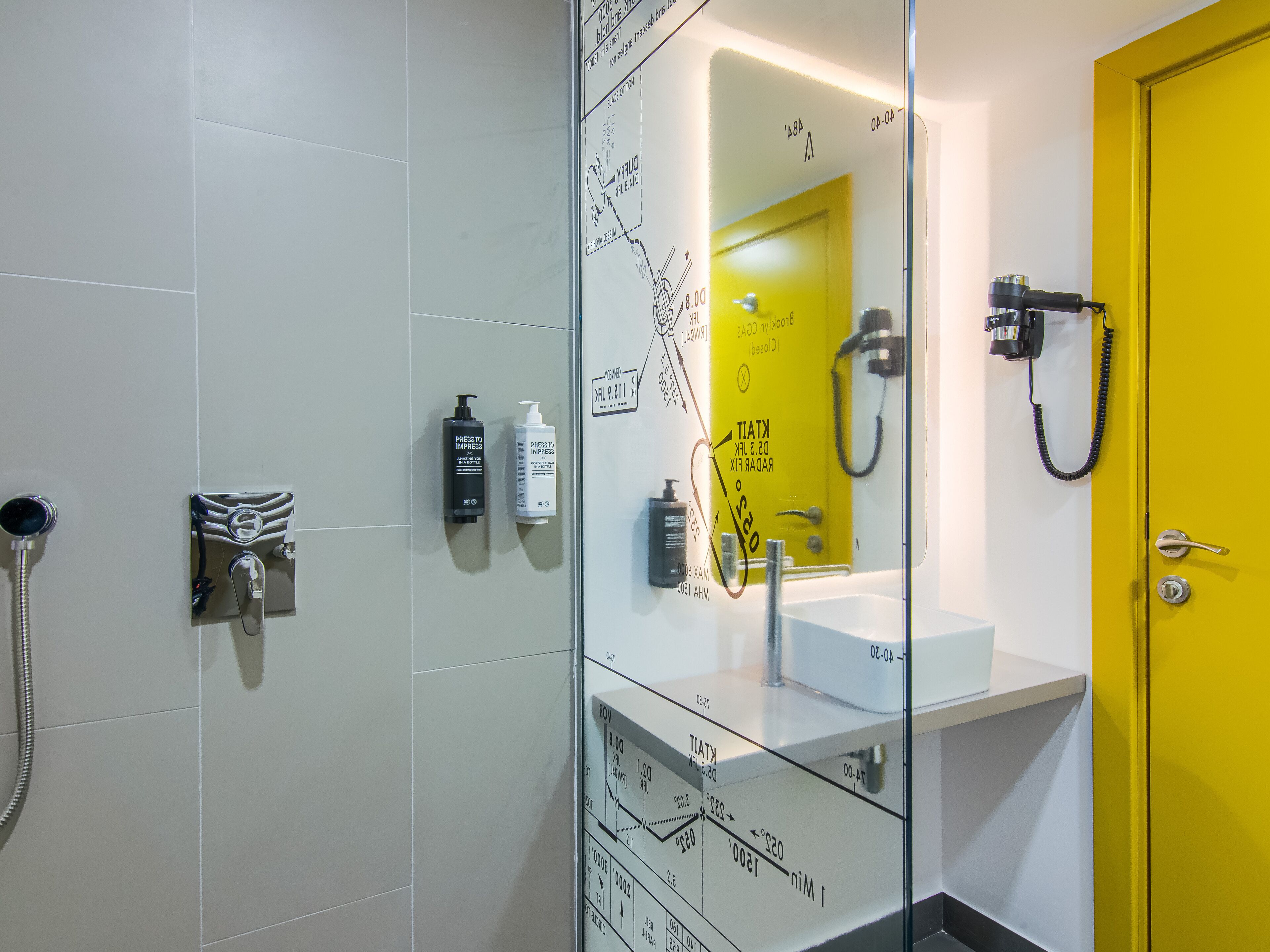 Casa de banho moderna com divisória de vidro, porta amarela e lavatório branco.