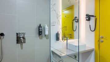 Casa de banho moderna com divisória de vidro, porta amarela e lavatório branco.