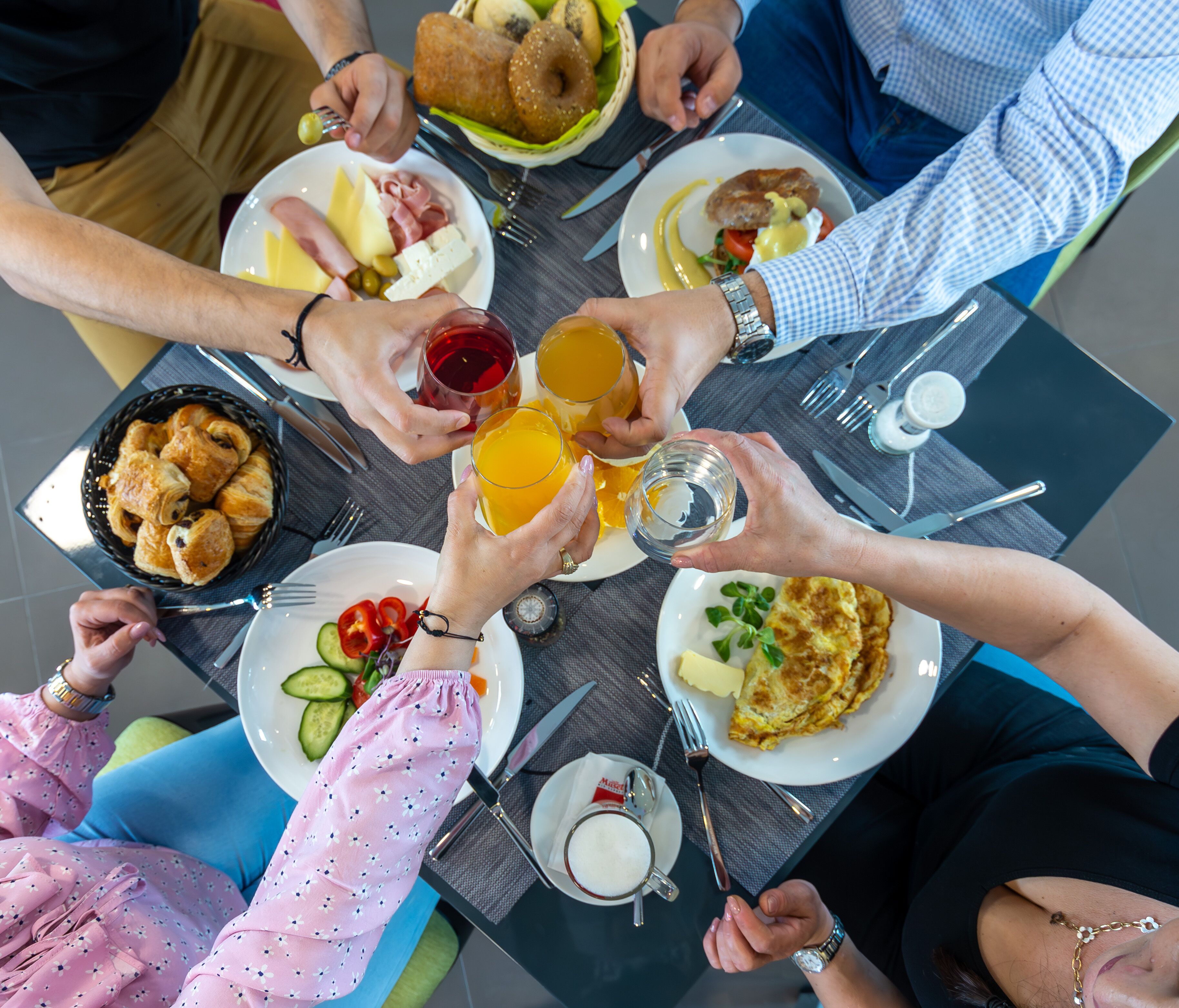 A group of people at a table with various dishes, drinks, and utensils.