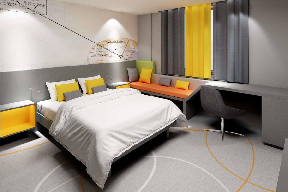 A modern hotel room with a large bed, a desk, and a seating area.