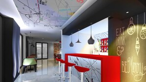 Un espace bar moderne avec des tabourets rouges, un présentoir à vin et un mur noir où sont écrits des messages à la craie.