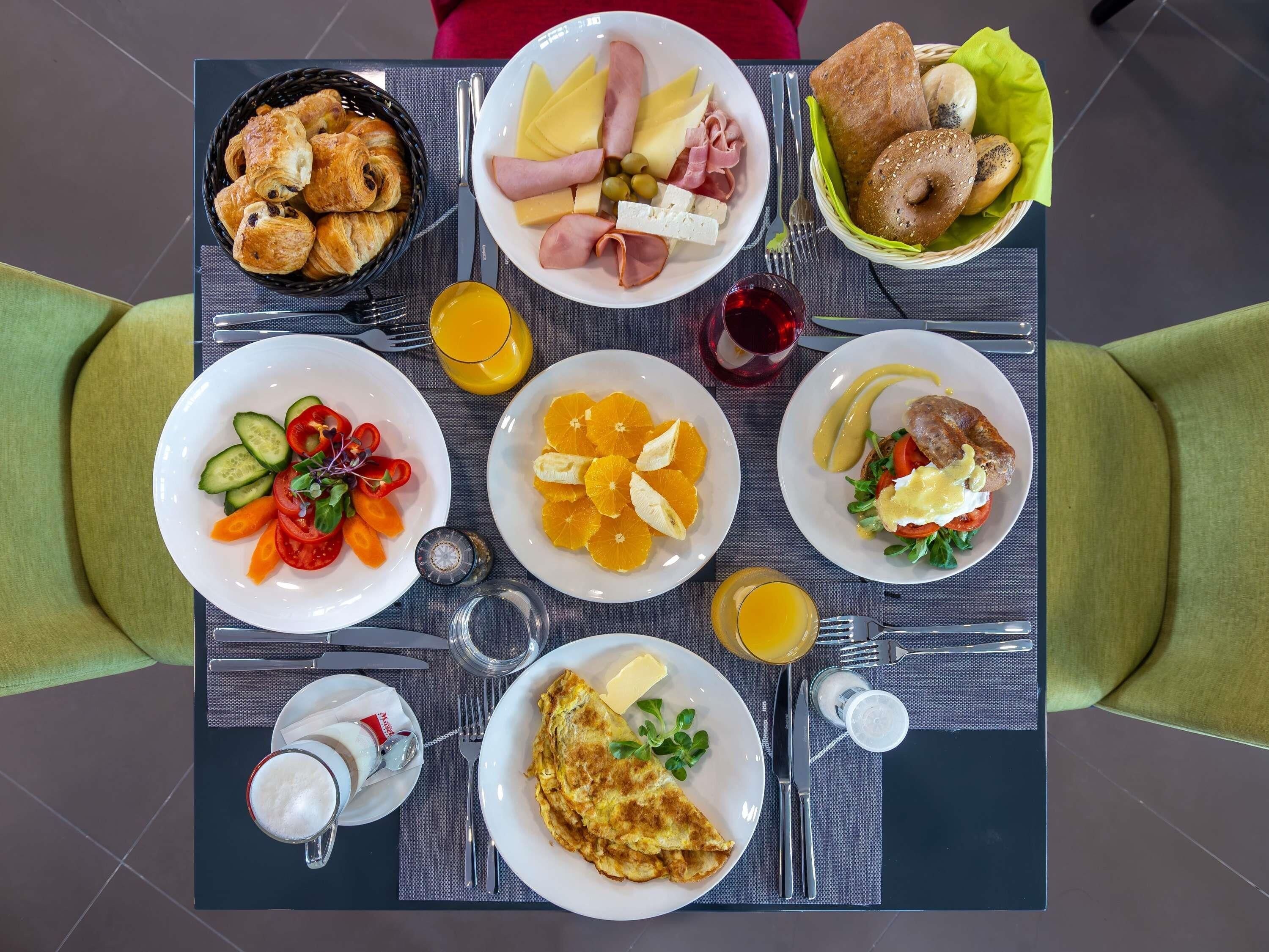 A breakfast table with various food items, including croissants, cheese, ham, and fruit.