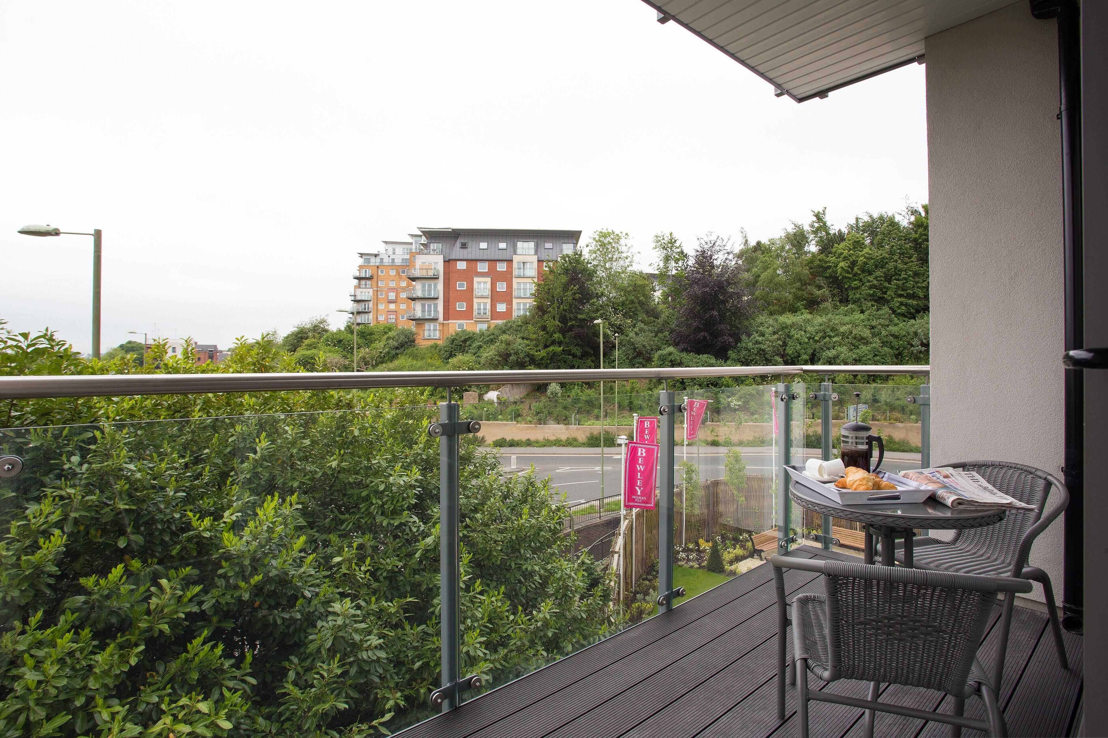 A balcony with a table, chairs, and a newspaper.