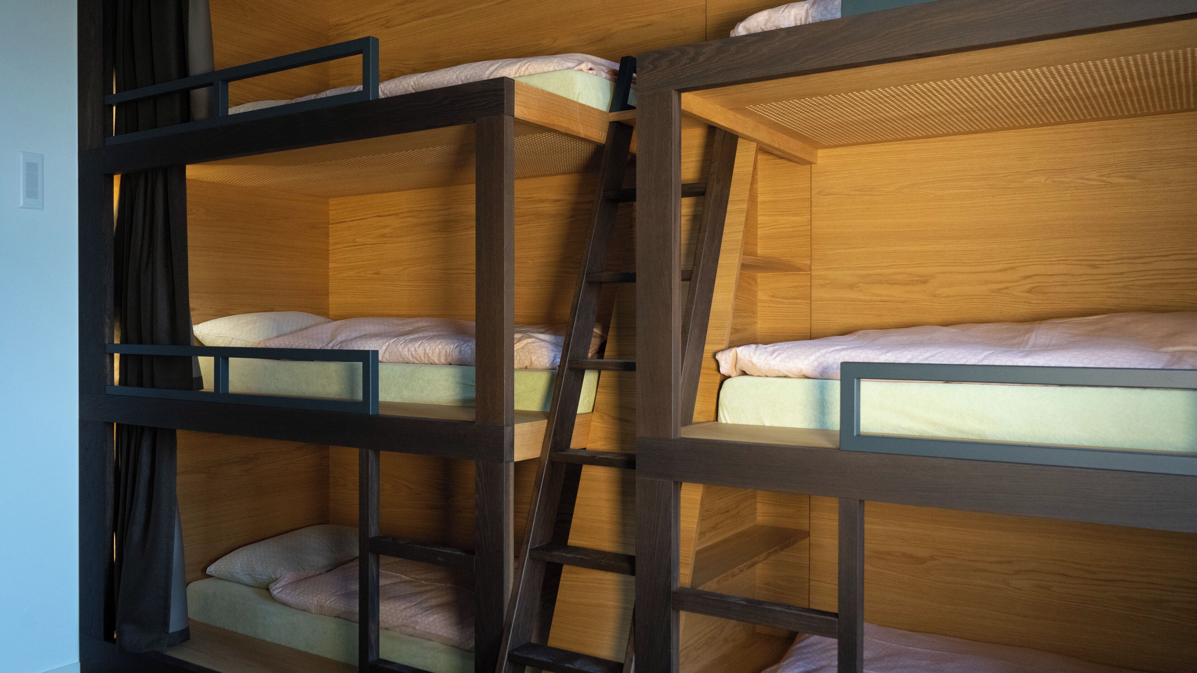 A bunk bed room with wooden frames and a ladder.