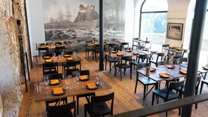 A restaurant with wooden tables and chairs, set against a mural of a river and castle. - Jugendherberge Schloss Burgdorf - Hostel (Burgdorf)