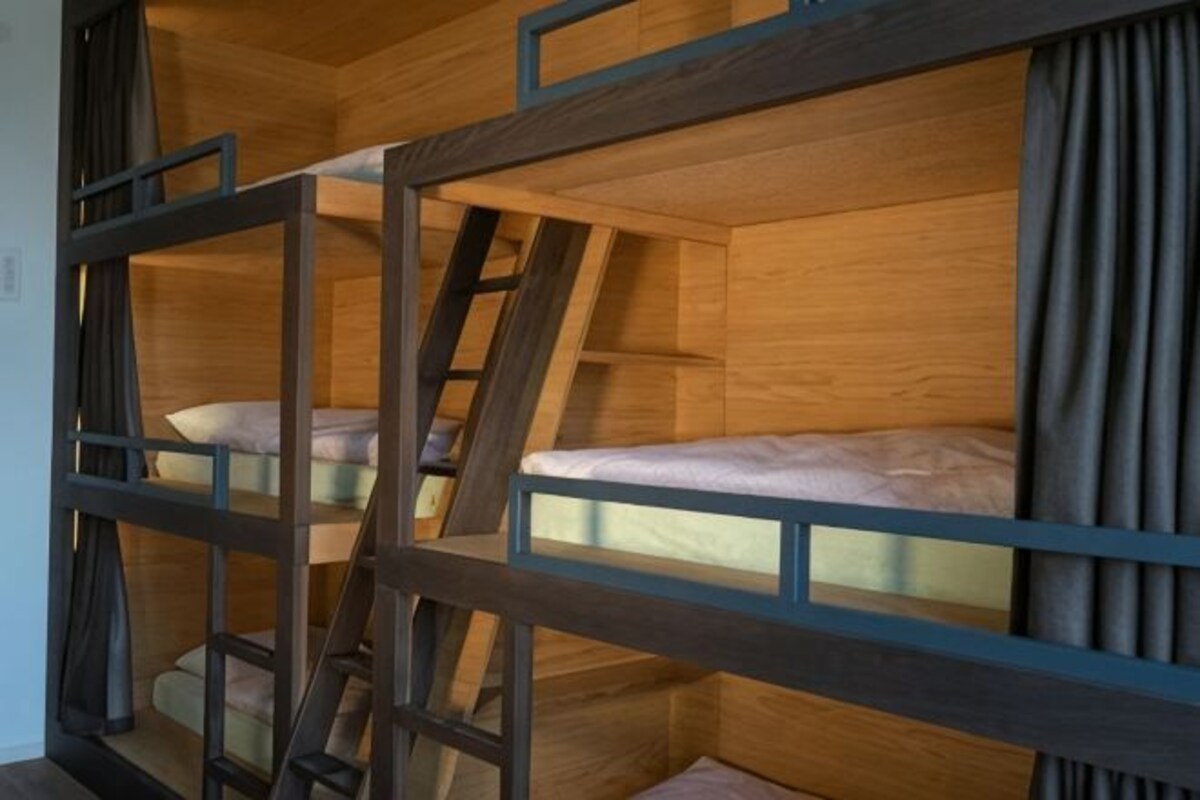 Een stapelbed met een ladder, houten wanden en gordijnen.